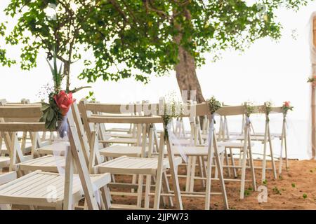 A simple beach wedding set up beside a tree on the seaside Stock Photo
