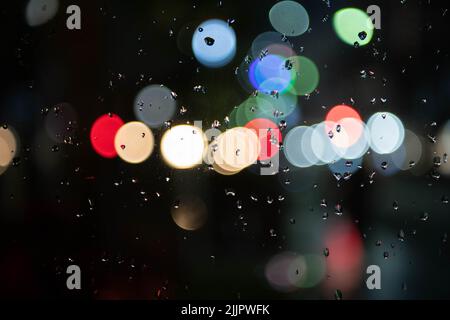 Image of raindrops on the window at night in the city, burry background, abstract bokeh, for background Stock Photo