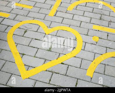 Yellow heart symbol on a parking lot and pavement Stock Photo