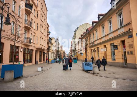 A view of people walking on a street surrounded by shops and restaurants in square of Poznan Stock Photo