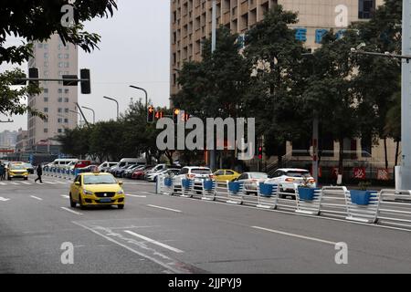 A view of a street in Chongqing, China with traditional yellow taxi and other vehicles moving Stock Photo