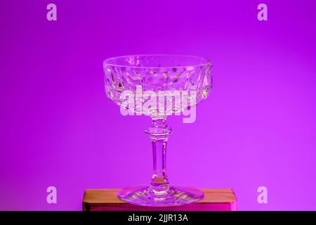 A crystal ice cream cup on a wooden stand on a purple background Stock Photo