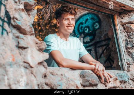 A blonde Spanish man smiling and leaning on the stone Stock Photo