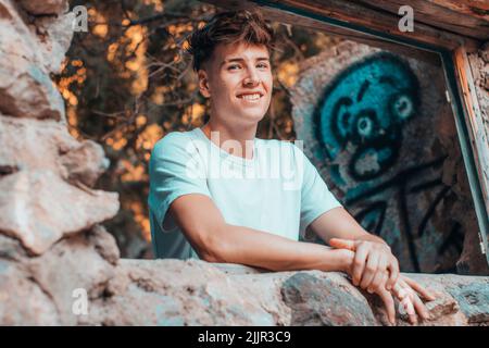 A blonde Spanish man smiling and leaning on the stone Stock Photo