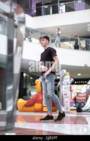 A vertical shot of an attractive Caucasian guy standing in a mall Stock Photo