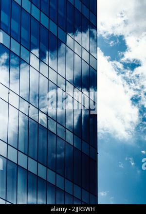 A vertical shot of the reflections of clouds on the facade of a modern building in Madrid, Spain Stock Photo
