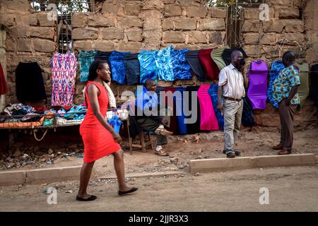 Nairobi, Kenya. 16th Mar, 2022. A woman walks past a group of men selling clothes by the streets in Kibera Slum, Nairobi. Life inside Kibera Africa's Largest Slum. (Photo by Donwilson Odhiambo/SOPA Images/Sipa USA) Credit: Sipa USA/Alamy Live News Stock Photo