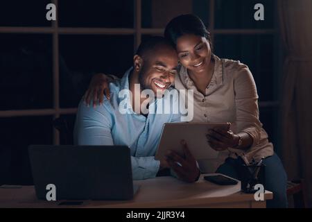 Ive been taking a trip down memory lane. a young couple using a digital tablet together at night. Stock Photo