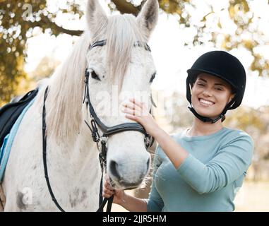 Hand on your horse and your heart in your hand. an attractive young woman standing with her horse in a forest. Stock Photo