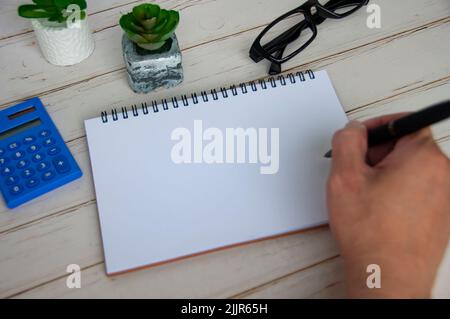 Hand holding black pen on blank white notepad with space customizable for text or ideas. Copy space Stock Photo