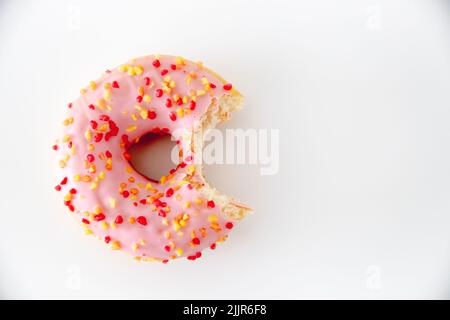 A closeup of a bitten pink glazed donut isolated on a white background with copy space Stock Photo