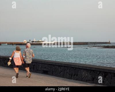 A retired couple walking on a promenade near the sea Stock Photo