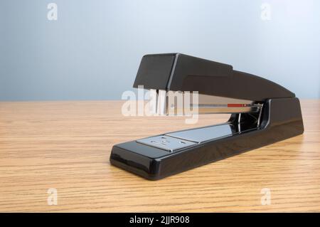 A close-up shot of a stapler on a wooden table Stock Photo