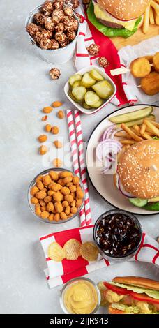 Various of american food, French fries, hamburgers, nuggets, hotdog, chips, popcorn, sauces on a white background, top view. Stock Photo