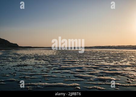 A scenic view of a beautiful sea captured from the shore during a mesmerizing sunset Stock Photo