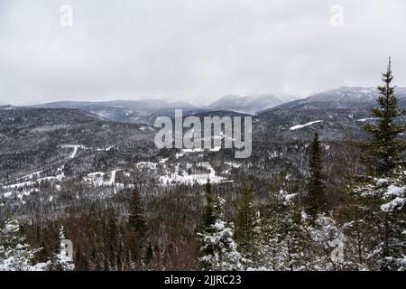 Beautiful background of snowy landscape with trees, clouds and fluffy snow and small town in mountain valley, ski resort concept Stock Photo