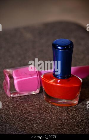 The pair of a red and a pink color nail paints on a blurred background Stock Photo