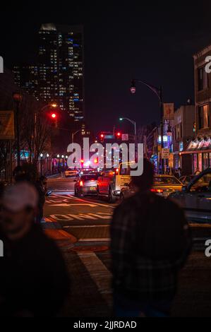 A road traffic next to a sidewalk with people at night Stock Photo