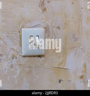 Old light switch on a shabby battered wall. Selective focus Stock Photo