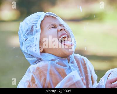 I wonder what rain tastes like. a little girl sticking her tongue out to catch the rain drops in her mouth. Stock Photo