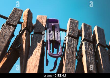 A closeup shot of wooden clothes pins hanging on rope against a blue sky Stock Photo