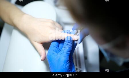 Manicurist specialist doing hardware manicure to client using special tools Stock Photo