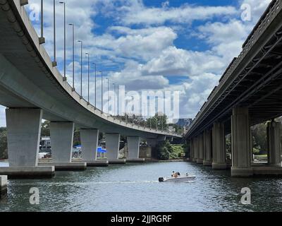 A boat sailing underneath Iron Cove Creek pedestrian bridge and Iron Cove Bridge at Bay Run Stock Photo