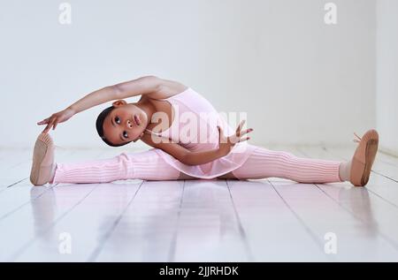 Warming up before practicing her routine. a little girl doing the splits in a ballet studio. Stock Photo
