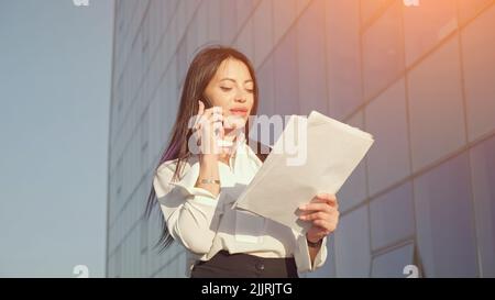 Manager walks talking on phone and looking at documents Stock Photo