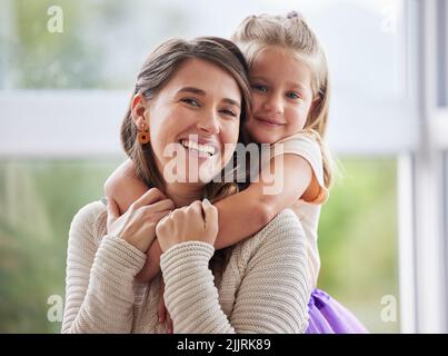 She keeps this smile on my face. a little girl giving her mother a hug at home. Stock Photo
