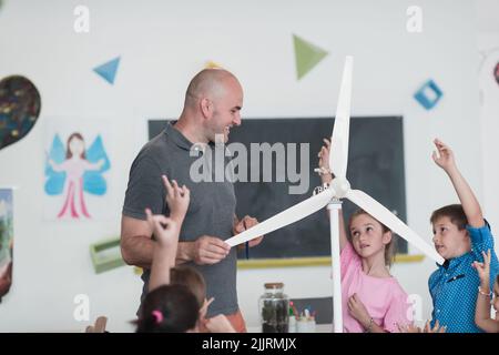Elementary School Stem Robotics Classroom Diverse Group of Children Building and Programming windmill ecology robot concept. Together Talking and Stock Photo