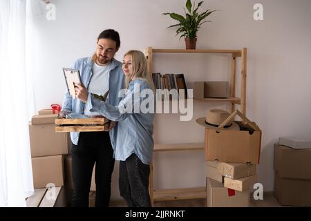 happy couple looking at photo and unpacking things at new home. people, family, memories and moving Stock Photo