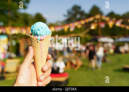 Ice cream cone in hand. Sweet dessert on summer picnic blurred background. Food, summer, ice cream concept. Selected focus. High quality photo Stock Photo
