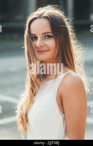 Gorgeous caucasian bride standing outdoors in her wedding dress, posing looking at camera. Female beauty portrait. Positive person. Attractive Stock Photo