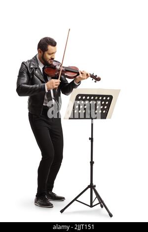Full length shot of a young modern man in a leather jacket playing a violin in front of a paper music stand isolated on white background Stock Photo