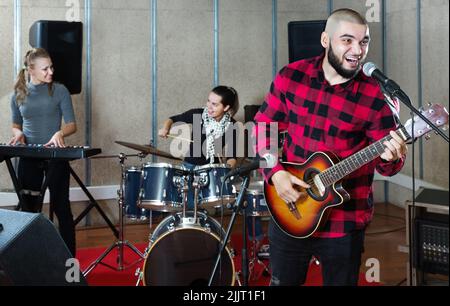 Bearded guy soloist playing guitar in studio Stock Photo