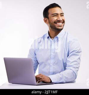 I feel extra confident in myself today. Studio shot of a young businessman using a laptop against a white background. Stock Photo