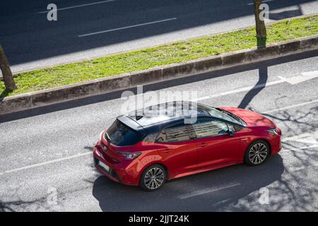 A photo of a red Toyota hybrid car driving on the streets of Lisbon Stock Photo