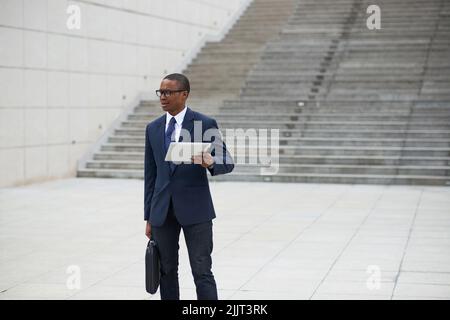 Young businessman with digital tablet standing outdoors Stock Photo