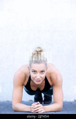 Attractive sporty woman concentrating in gym while doing fitness exercises. Young perfect shaped blonde doing plank. High quality photo Stock Photo