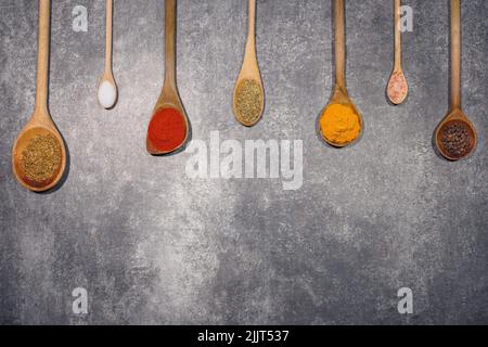 A top view of wooden spoons with various spices isolated on gray background with copy space Stock Photo
