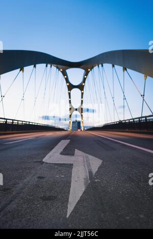 A vertical shot of a bridge and a huge arrow pointing on the right painted on the ground Stock Photo
