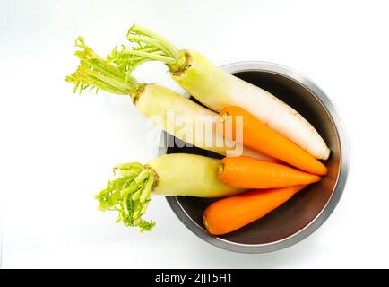 Organic carrots and white radishes in round shape stainless steel bowl, unpeeled carrots and radishes, top view image, isolated image on white backgro Stock Photo