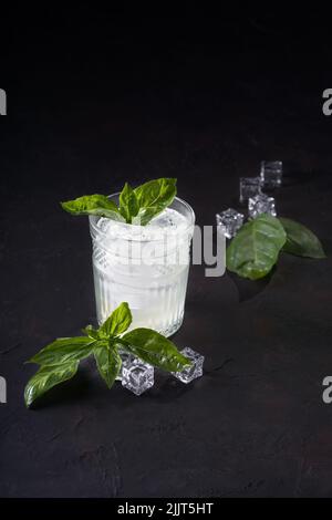 Gin or vodka with mint slices of lemon and ice on a dark background. Alcohol cocktail with citrus and basil. Copy space. Stock Photo