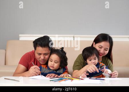 Parents and theis children drawing together at home Stock Photo