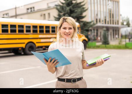 Teacher of elementary school near the school bus Stock Photo - Alamy