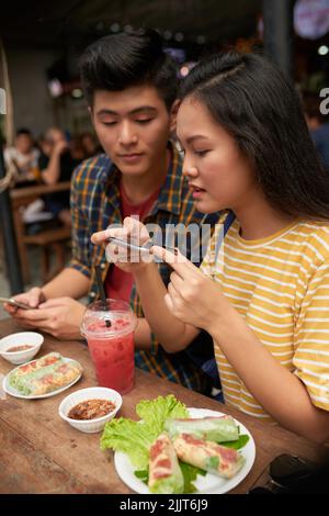 Couple taking photos of food they ordered in cafe Stock Photo