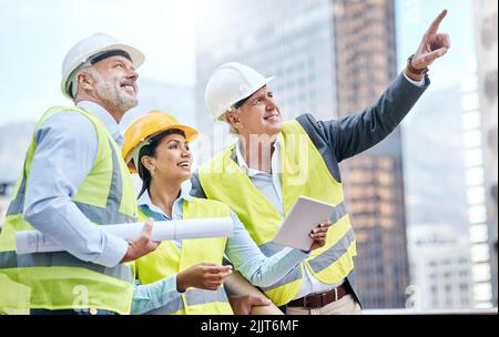 Covering all aspects of their big build. a group of businesspeople using a digital tablet while working at a construction site. Stock Photo