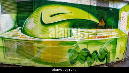 A shot of a social graffiti street art painting of neon green creature sitting in toxic water on wall Stock Photo