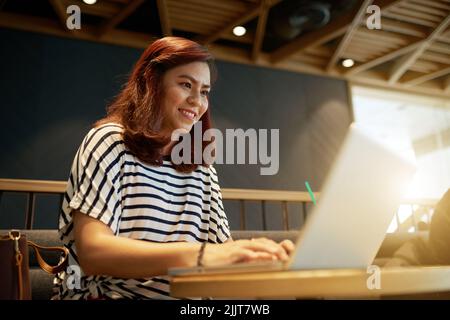 Cheerfu Asian young woman working at outsourse Stock Photo